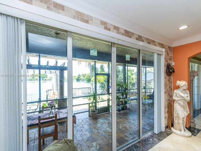 interior space with brick wall, crown molding, and a water view