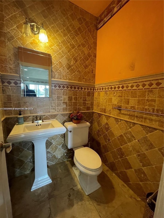 bathroom featuring toilet and tile walls