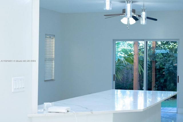 interior space with ceiling fan and light stone countertops