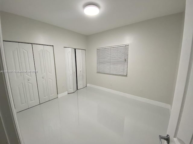 unfurnished bedroom featuring multiple closets and light tile patterned floors