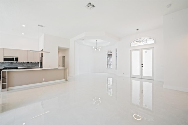 unfurnished living room featuring french doors, an inviting chandelier, and light tile patterned floors