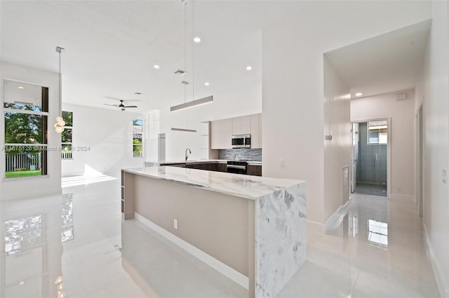 kitchen with ceiling fan, pendant lighting, light tile patterned floors, stainless steel appliances, and light stone countertops