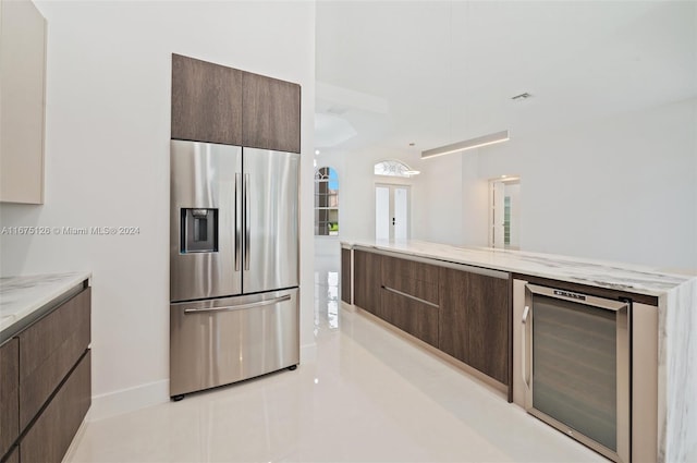 kitchen with stainless steel fridge, light stone counters, wine cooler, and light tile patterned floors