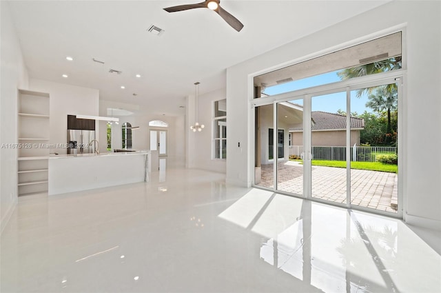 unfurnished living room featuring ceiling fan with notable chandelier and light tile patterned floors