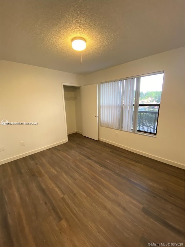 unfurnished bedroom with a closet, dark hardwood / wood-style floors, and a textured ceiling