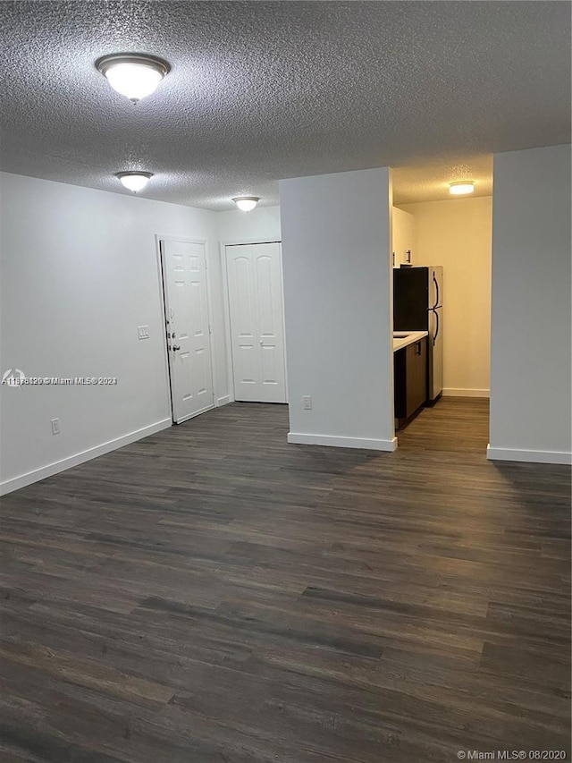 spare room featuring dark wood-type flooring and a textured ceiling