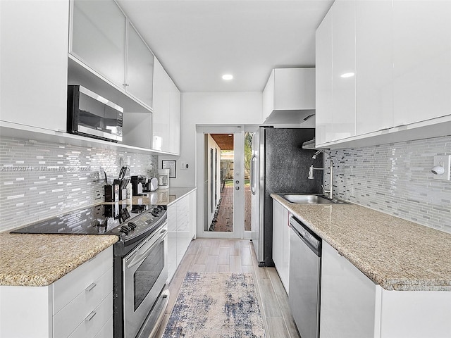 kitchen with light hardwood / wood-style flooring, white cabinetry, stainless steel appliances, and backsplash