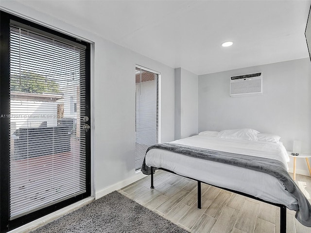 bedroom with a wall mounted air conditioner and light hardwood / wood-style floors