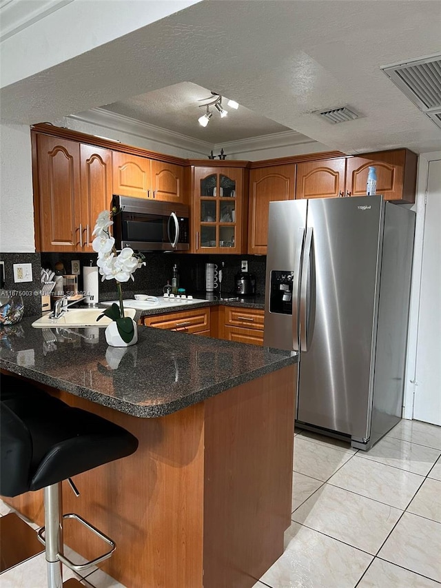 kitchen featuring tasteful backsplash, dark stone countertops, kitchen peninsula, appliances with stainless steel finishes, and a textured ceiling