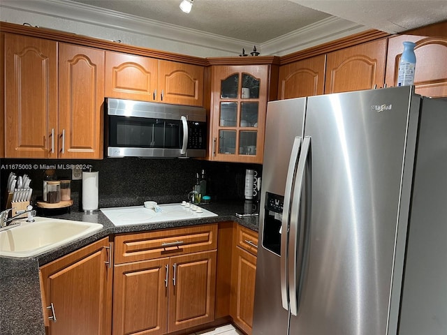 kitchen featuring backsplash, sink, ornamental molding, appliances with stainless steel finishes, and a textured ceiling