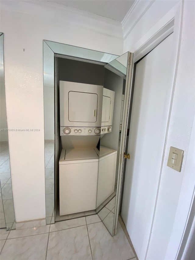 washroom with stacked washer and dryer and crown molding