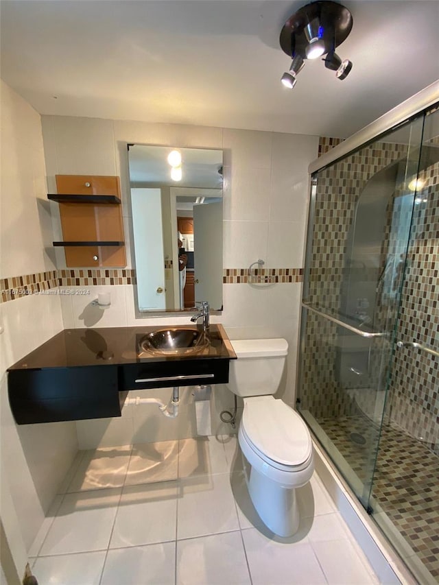 bathroom featuring walk in shower, toilet, tile patterned floors, sink, and tile walls