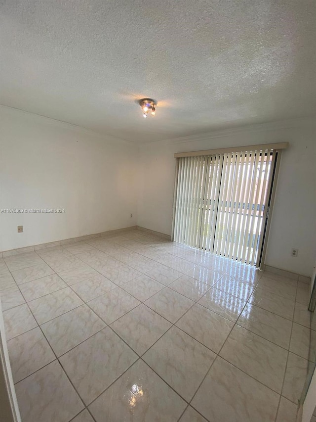 spare room with a textured ceiling and light tile patterned floors