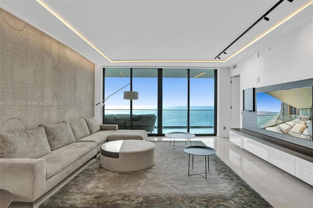 living room featuring a water view, a healthy amount of sunlight, and floor to ceiling windows