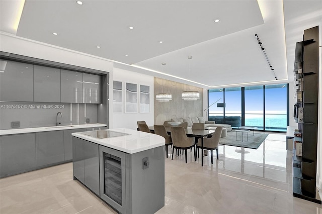 kitchen featuring a kitchen island, gray cabinetry, beverage cooler, black electric stovetop, and a water view