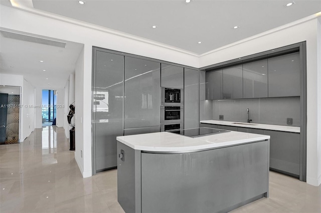 kitchen featuring stainless steel appliances, gray cabinets, a kitchen island, and sink