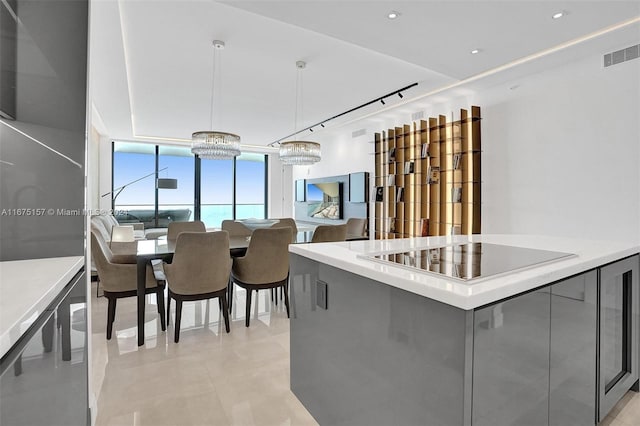 kitchen with black electric cooktop, hanging light fixtures, a chandelier, and gray cabinetry