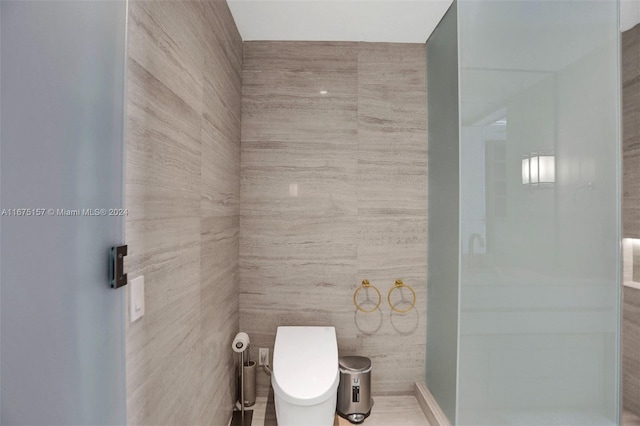 bathroom with toilet and tile walls