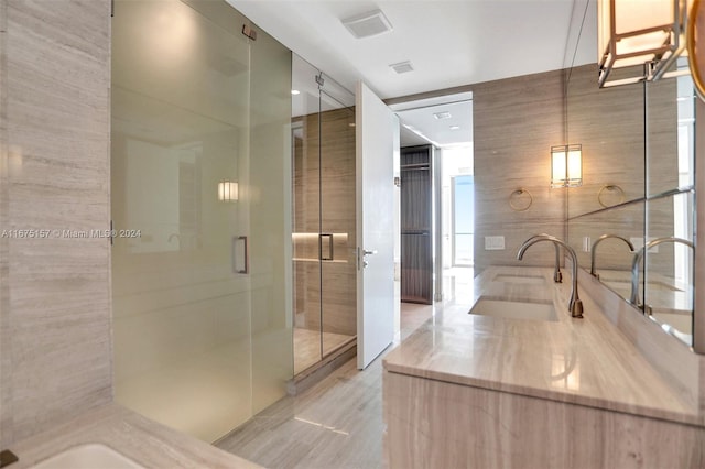 bathroom featuring walk in shower, vanity, and tile walls