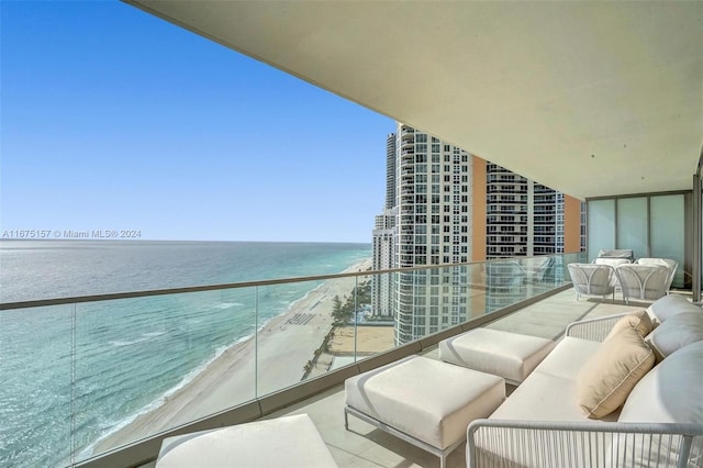 balcony with a view of the beach, a water view, and an outdoor living space