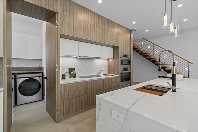 kitchen featuring light stone counters, hanging light fixtures, sink, white cabinetry, and washer / dryer