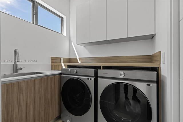 washroom featuring sink, cabinets, and washer and clothes dryer