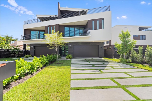 contemporary home featuring a front lawn, a balcony, and a garage