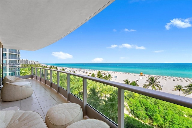 balcony with a water view and a view of the beach