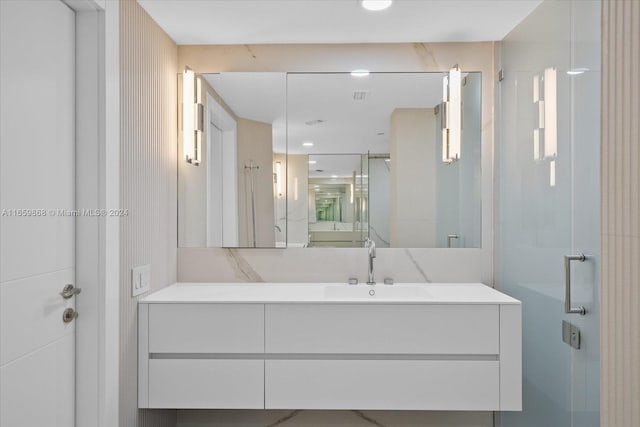 bathroom featuring a shower with shower door and vanity