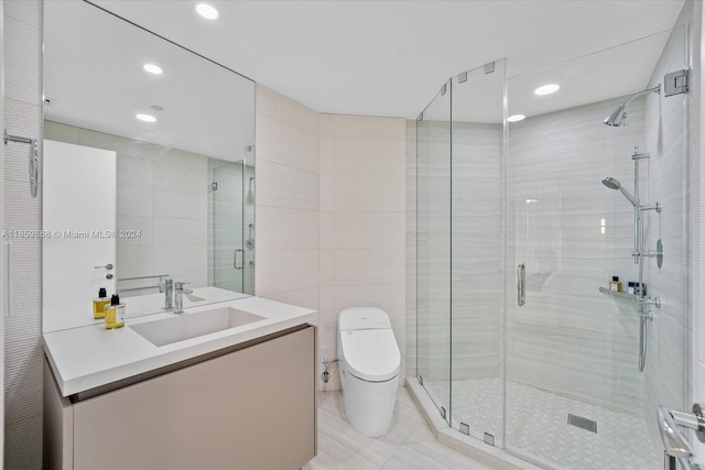 bathroom with tile walls, a shower with shower door, vanity, and toilet