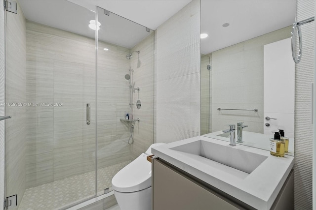 bathroom featuring a shower with shower door, vanity, and toilet