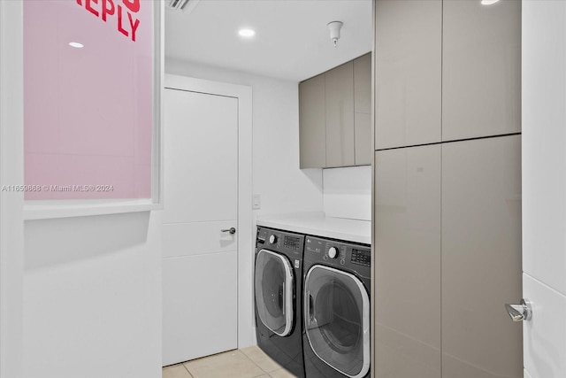 laundry area featuring cabinets, light tile patterned floors, and washing machine and clothes dryer