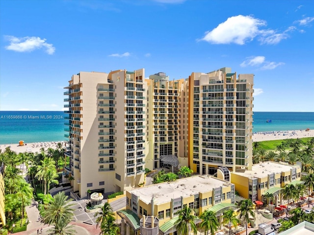 view of building exterior featuring a water view and a beach view