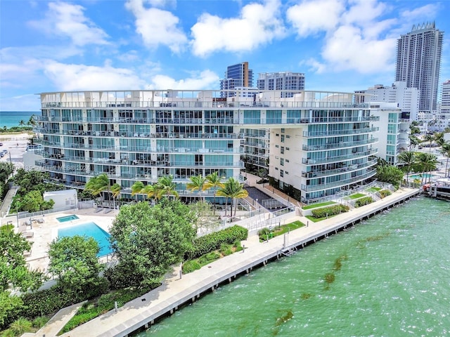 view of building exterior with a water view and a community pool