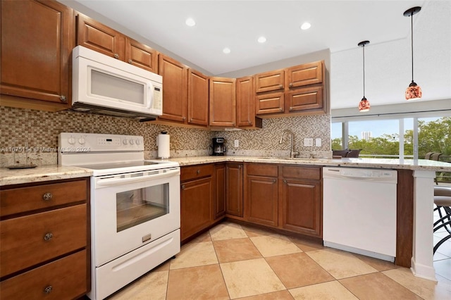 kitchen with tasteful backsplash, sink, pendant lighting, light stone counters, and white appliances