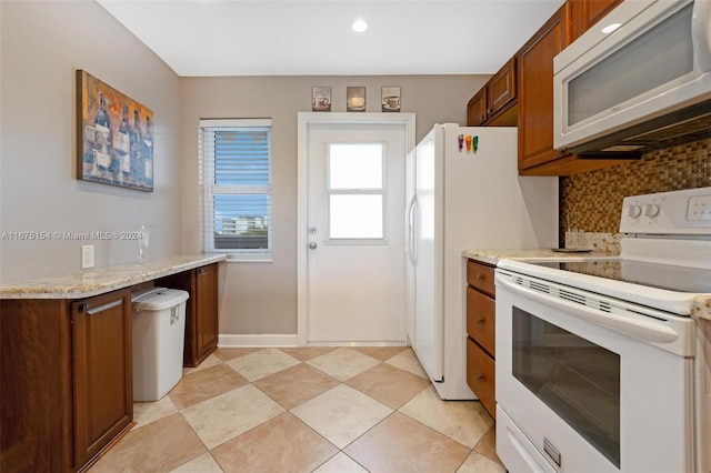 kitchen with decorative backsplash, light stone counters, and white appliances