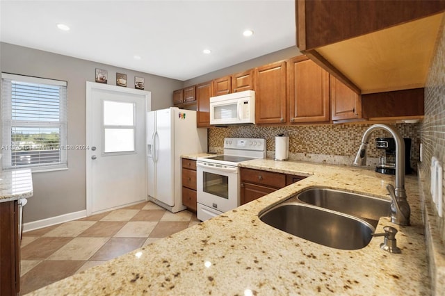 kitchen featuring sink, decorative backsplash, light stone counters, and white appliances