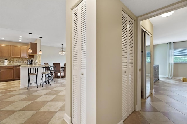 hall with light tile patterned flooring, sink, and an inviting chandelier