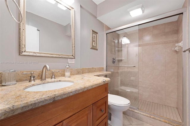 bathroom featuring a shower with door, vanity, toilet, and tile patterned flooring