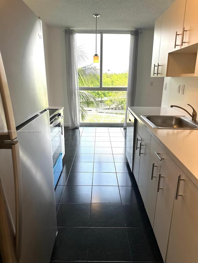 kitchen featuring stainless steel fridge, stove, decorative light fixtures, sink, and a textured ceiling