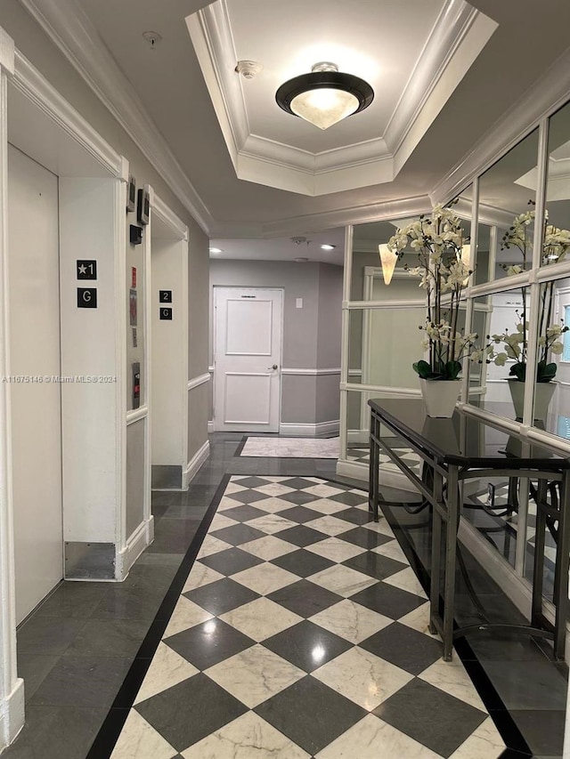 hall with a tray ceiling, ornamental molding, and elevator