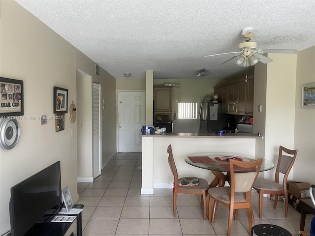 tiled dining area with ceiling fan and a textured ceiling