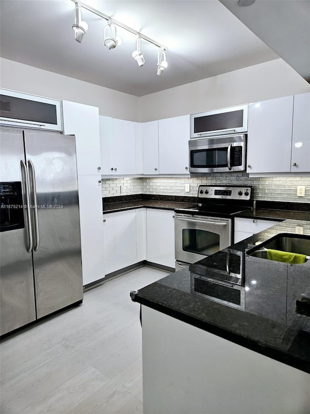 kitchen featuring white cabinets, appliances with stainless steel finishes, decorative backsplash, and light hardwood / wood-style flooring