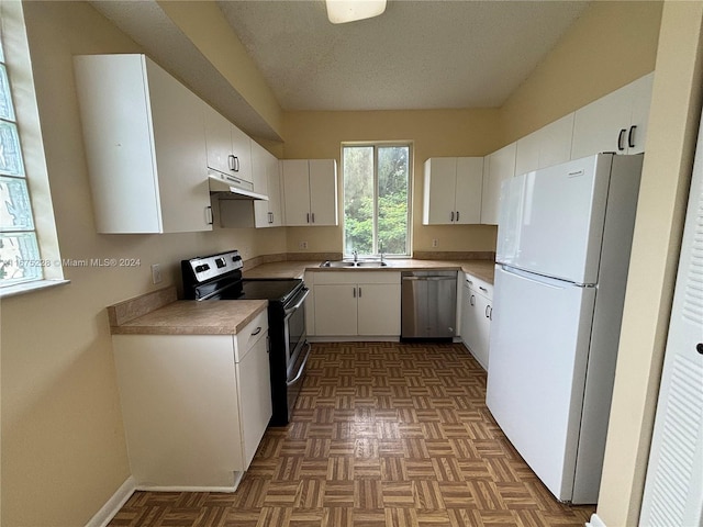 kitchen with dark parquet flooring, white cabinetry, sink, and stainless steel appliances