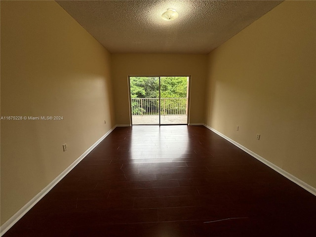 empty room featuring dark wood-type flooring and a textured ceiling