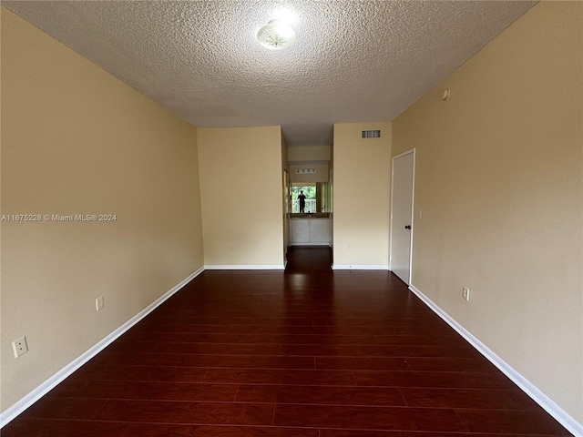 unfurnished room with a textured ceiling and dark hardwood / wood-style flooring