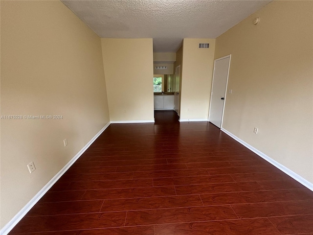 unfurnished room with dark wood-type flooring and a textured ceiling