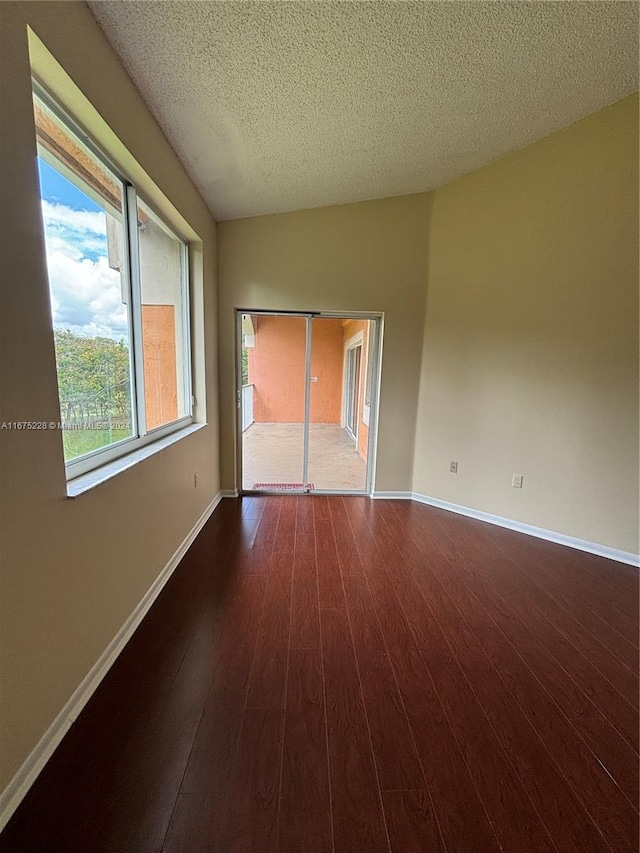 empty room featuring a textured ceiling and dark hardwood / wood-style flooring