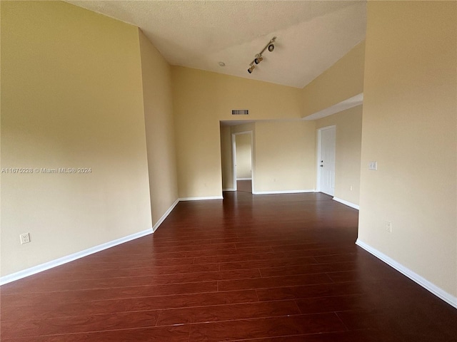 empty room with dark wood-type flooring, high vaulted ceiling, track lighting, and a textured ceiling