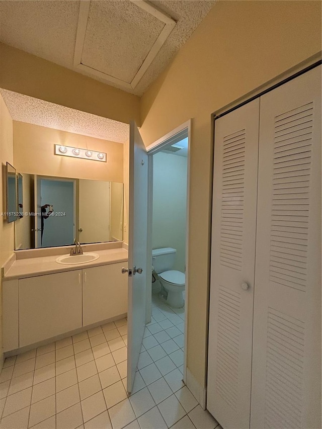 bathroom with toilet, tile patterned flooring, and vanity